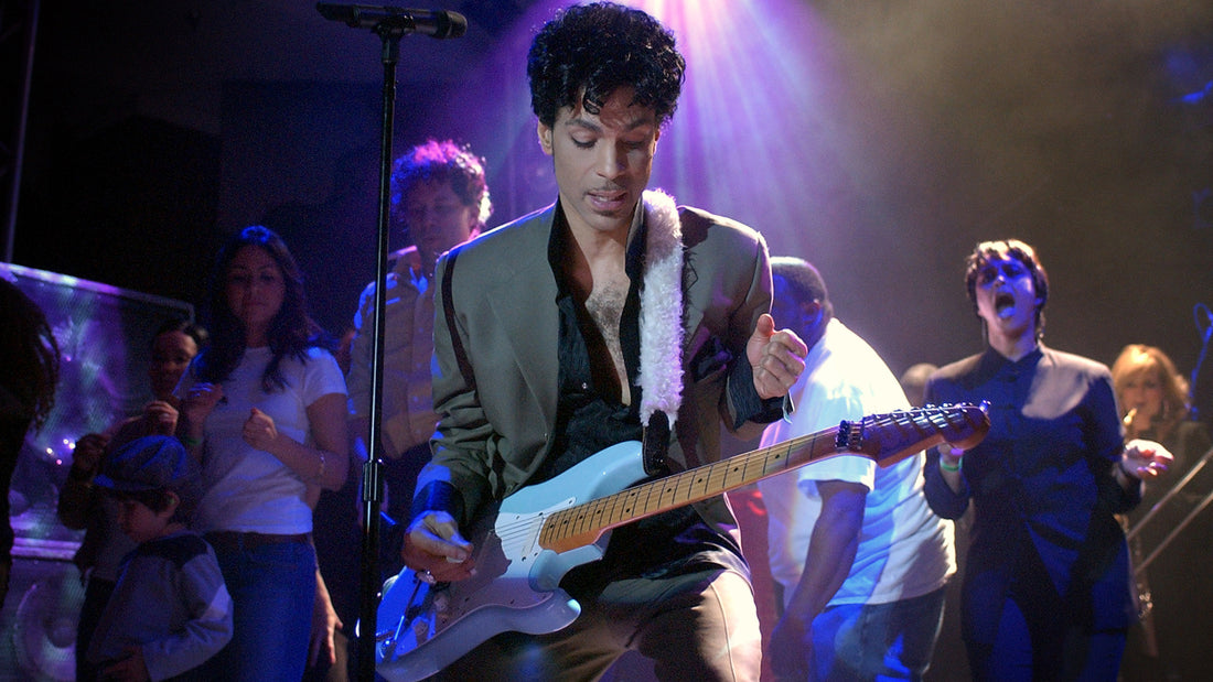 Prince performing live with guitar in hand, showing how his playing fit into his larger stage identity.