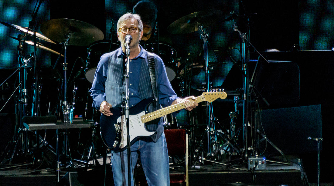 Eric Clapton playing guitar onstage with a focused, controlled posture
